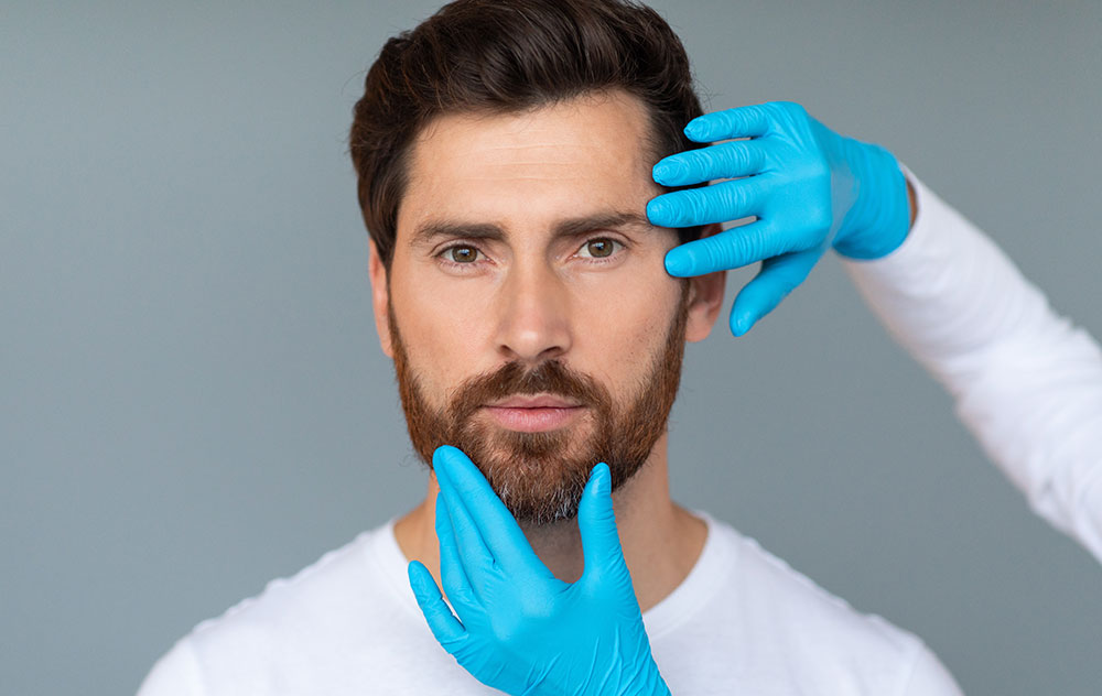 Cosmetician hands in protective medical gloves touching male face