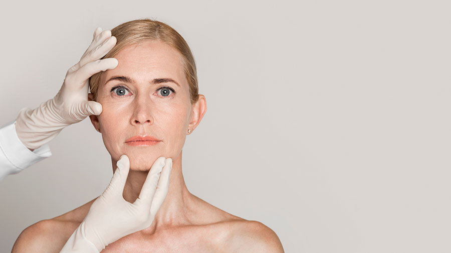 Dermatologist touching face of mature woman